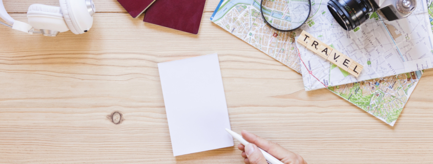 una persona escribiendo en papel con accesorios de viajero sobre fondo de madera
