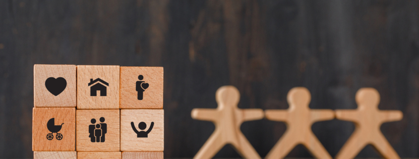 family concept with icons on wooden cubes, human figures on wooden background side view.