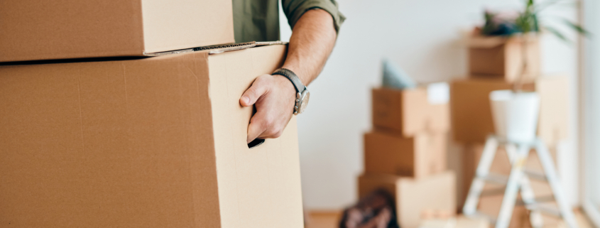 close up of man carrying cardboard boxes while relocating into n